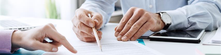 Business people pointing and talking about insurance agreements/documents with a pen marking different key areas in the contract.