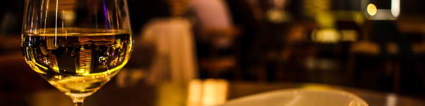 Upclose photo of white wine in glass with a side portion of chips in a restaurant