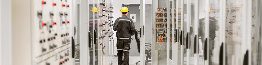 Gnetleman walking through software room with yellow hat on and overalls. 