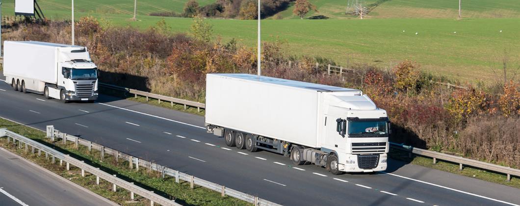 Two white lorries following each other down the motorway